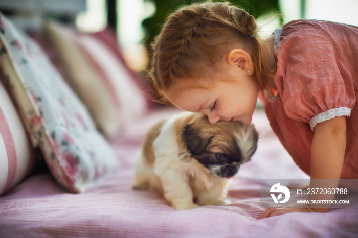 cute baby girl cuddling with puppy dog on summer patio at home