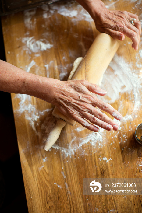 Overhead view of mature woman rolling dough on countertop