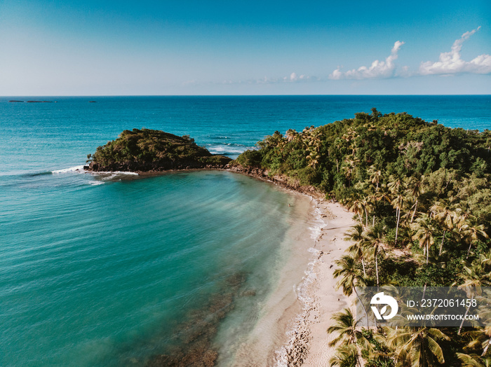 Aerial drone panoramic view of the paradise beach with sandy and rocky shore, palm trees and blue wa