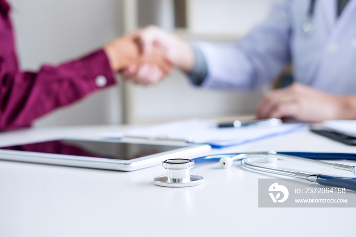 Professional Male doctor in white coat shaking hand with female patient after successful recommend t