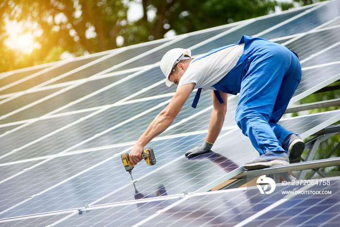 Construction worker connecting photo voltaic panel to solar system using screwdriver on shiny surfac