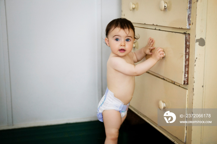 Portrait of baby girl opening drawer