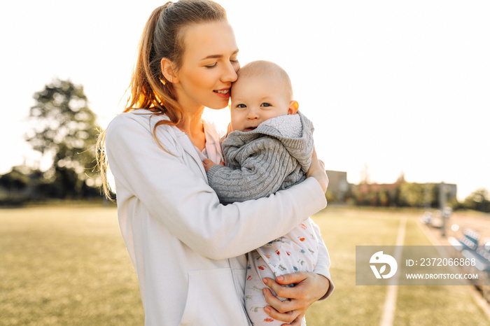 Happy mom plays, hugs and kisses her little son outdoors.Happy womens day.Family holiday and unity.