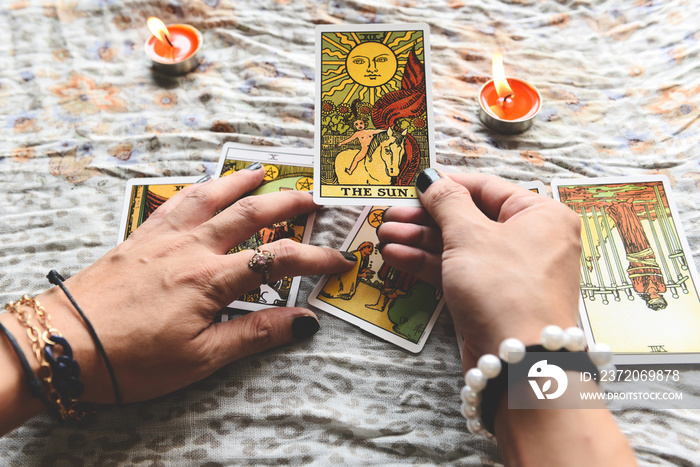 Show fortune tellers of hands holding tarot cards and tarot reader with candle light on the table, P