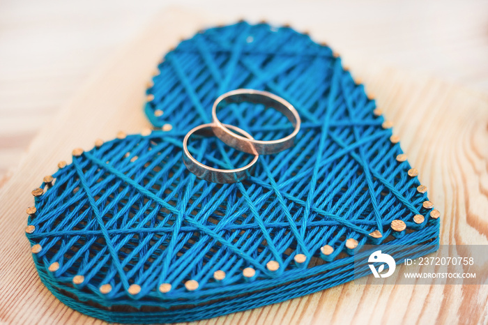 Close up view on string art heart with two wedding rings on it. Wedding decor concept idea