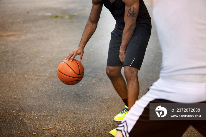 Mid section of men playing basketball on court