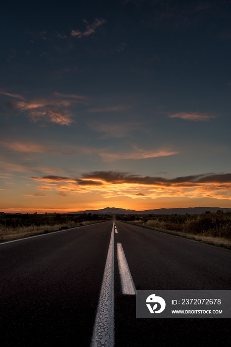 Straight highway road to a dramatic fiery sunset