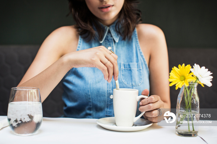 Midsection of woman having coffee in cafe