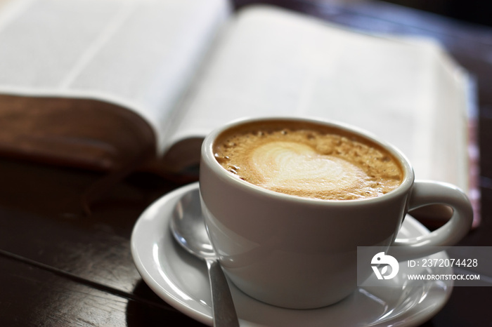 一杯拿铁咖啡，放在一本西班牙语基督教圣经旁边的桌面上。