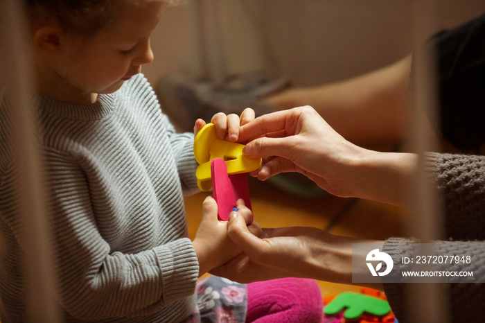 Cropped hands of mother assisting daughter in arranging colorful alphabets at home