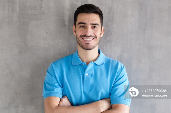 Portrait of smiling handsome man in blue polo shirt, standing with crossed arms isolated on grey tex