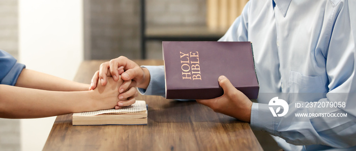 Close up hand. Asian man holding a Bible and a womans hand is a sign of love for Jesus or God. Acco