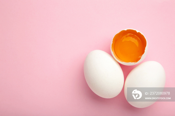 White eggs and egg yolk on the pink background. Easter concept. Vertical foto