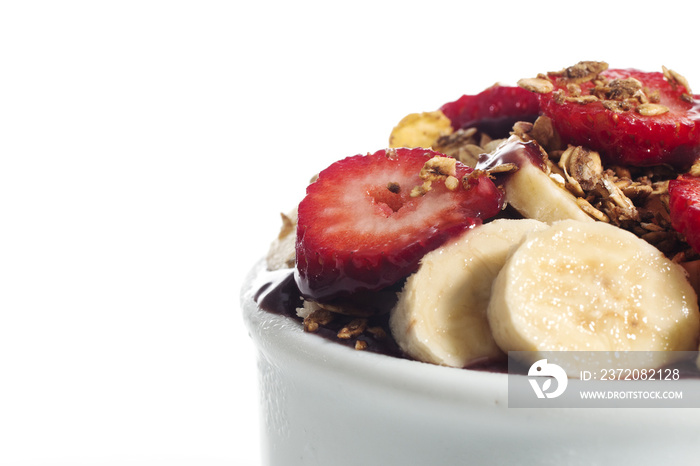 Acai cream with banana and strawberry in bowl isolated over white background.