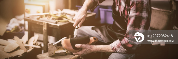 Cobbler holding a knife and a shoe