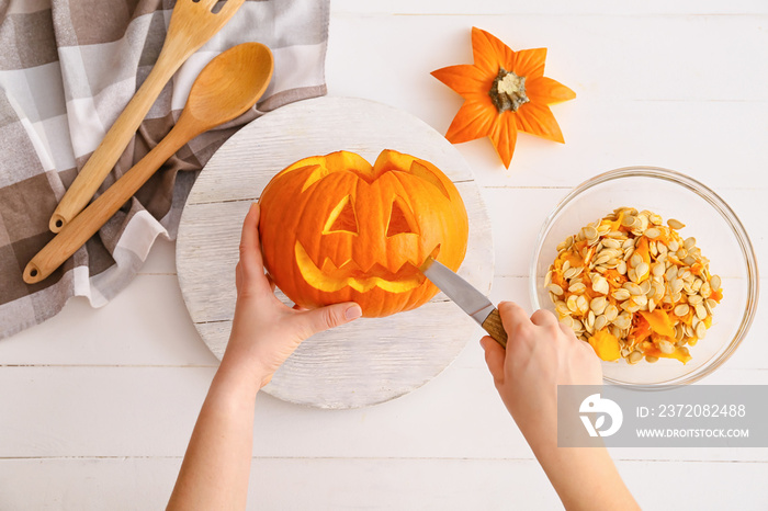 Woman carving pumpkin for Halloween at table