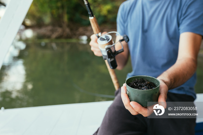 close up of man holding fishing bait earth worms outdoors on river