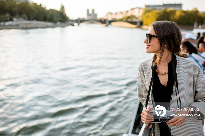 Young woman enjoying beautiful landscape view on the riverside from the ship during the sunset in Pa