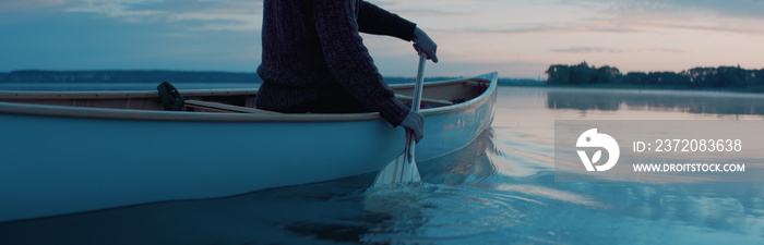 黎明时分，一名男子独自在一个大湖上划独木舟，画面特写