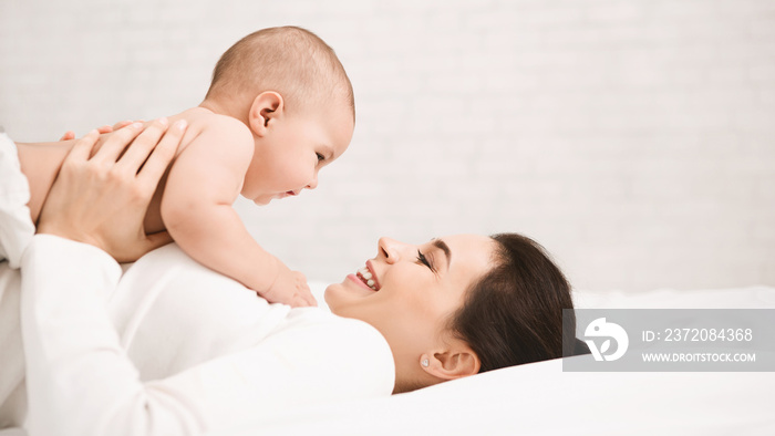 Mother with baby on bed having good time