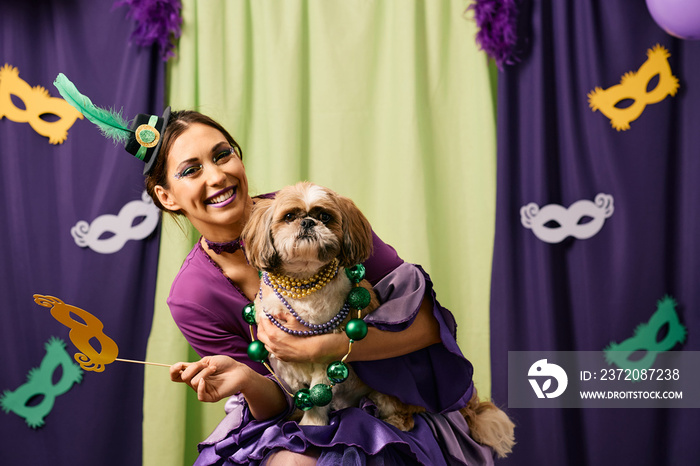 Happy woman and her dog in Mardi Gras costumes have fun carnival party and looking at camera.