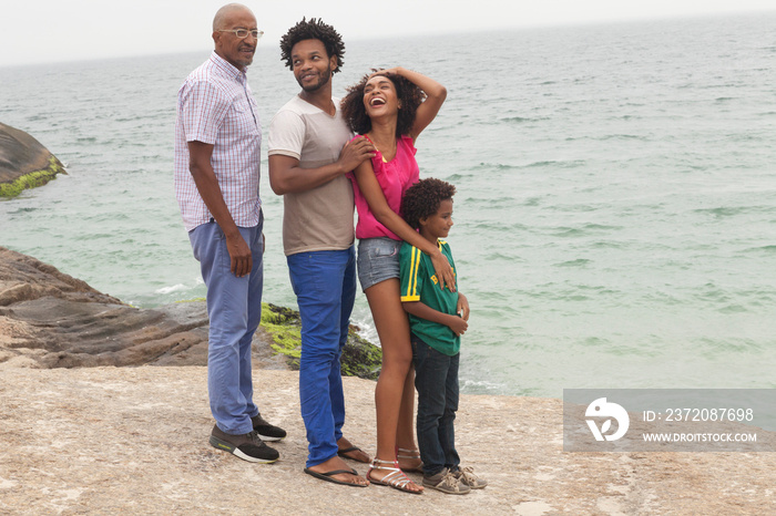 Grandfather and family standing on rock,  Ipanema Beach, Rio De Janeiro, Brazil