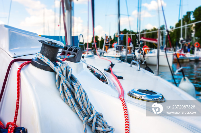 Detail of a sailboat deck with a winch and nylon ropes.