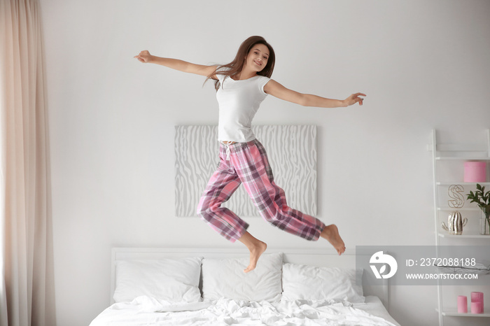 Young woman jumping on bed at home