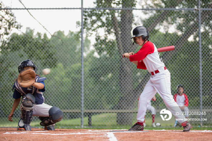 Young ball player watching pitch go past the plate