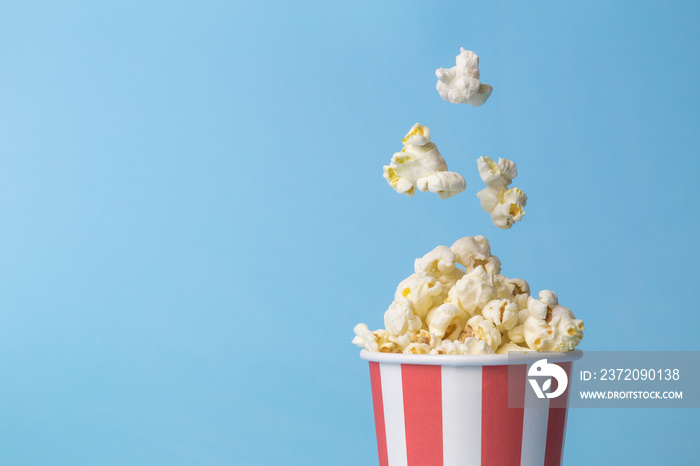 Falling popcorn in box isolated on blue.