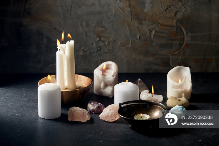 occult science and supernatural concept - burning candles, stones and crystals for magic ritual on s