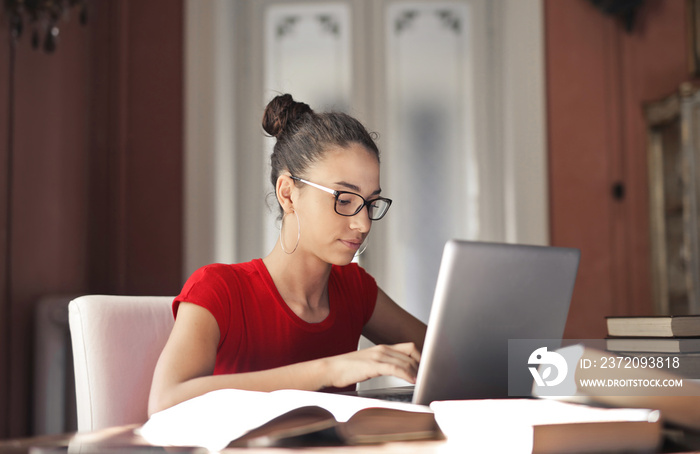 young woman studies in front of a computer at home