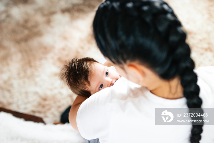 幸福的妈妈在白色的床上用母乳喂养她的新生儿