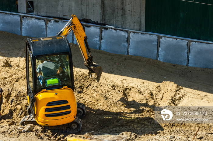 Yellow mini excavator working at the construction site