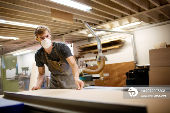 Carpenter wearing mask working in workshop