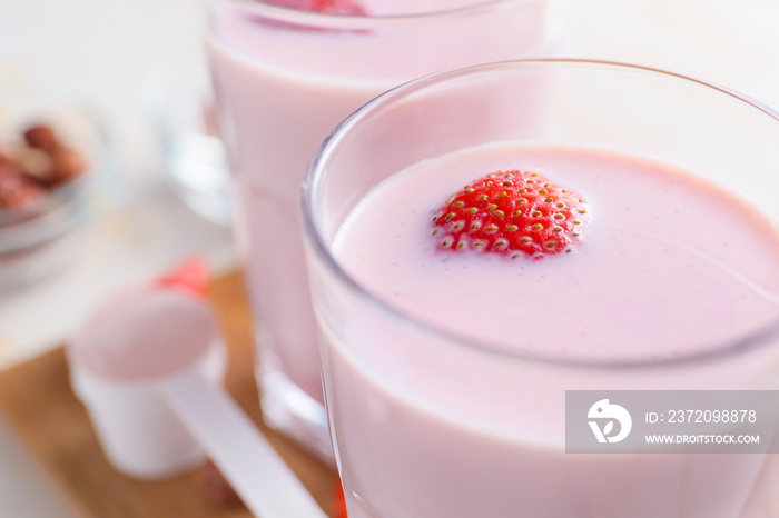 Glass of strawberry protein shake on table, closeup