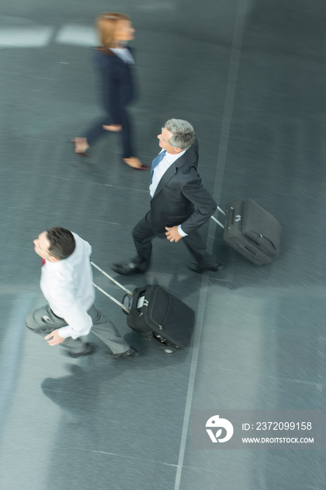 Businessmen running with suitcases in airport