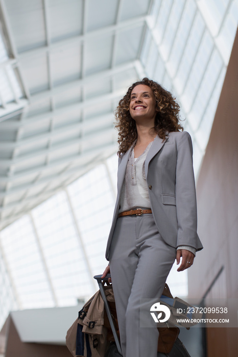 Smiling businesswoman with suitcase in airport