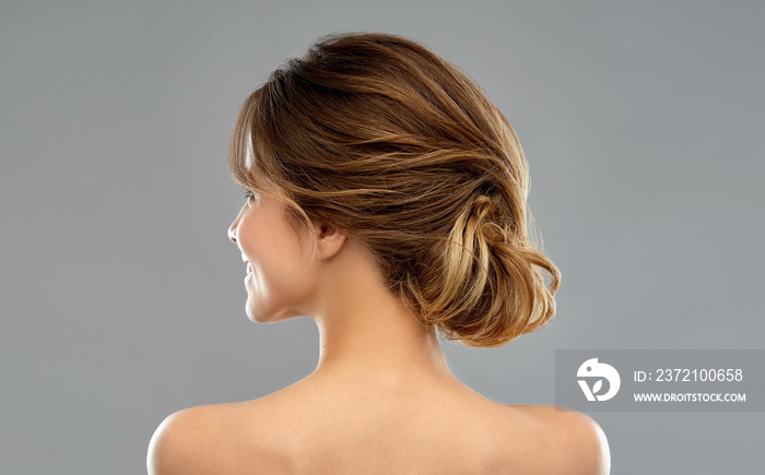 beauty and people concept - young woman with bare shoulders from back over grey background