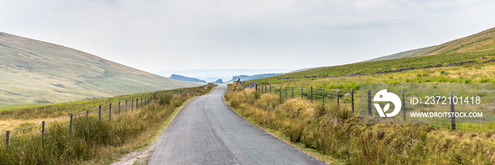 Typical landscape of Brecon Beacons National Park with mountians, trees and stone walls along the sm