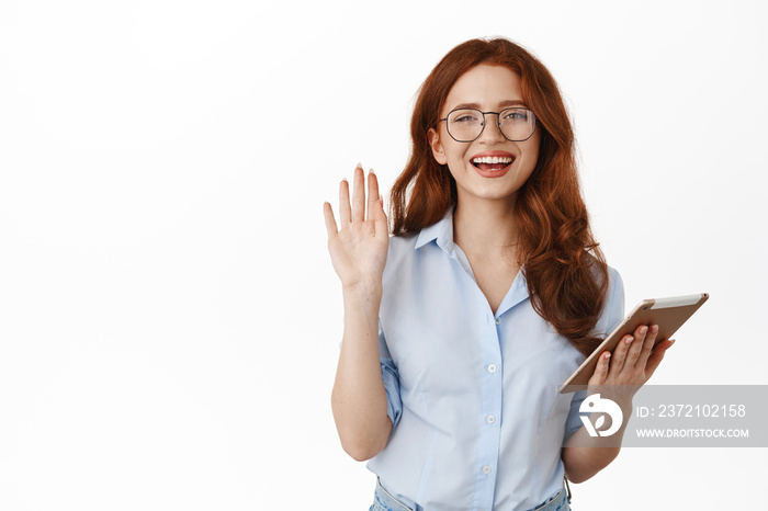 Attractive young office manager, female ceo coworker waving hand saying hi, holding digital tablet a