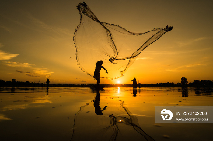 Silhouette of Fisherman catching fish in lake by using fishing net at beautiful sunset time.