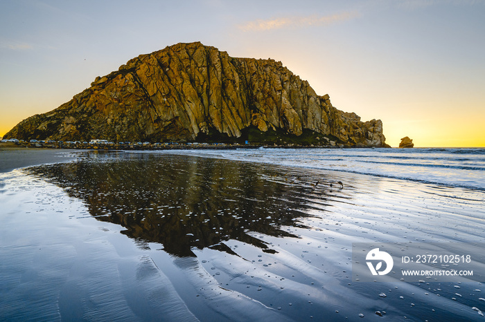 Moro Rock in Morro Bay, California, beautiful reflection in the water, blue waves and colorful sky