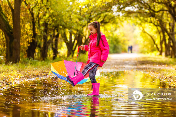 Adorable toddler girl with colorful umbrella outdoors at autumn rainy day