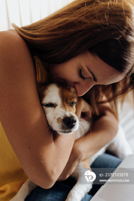 Close up of a beautiful woman kissing her dog Jack Russell Terrier at sunset