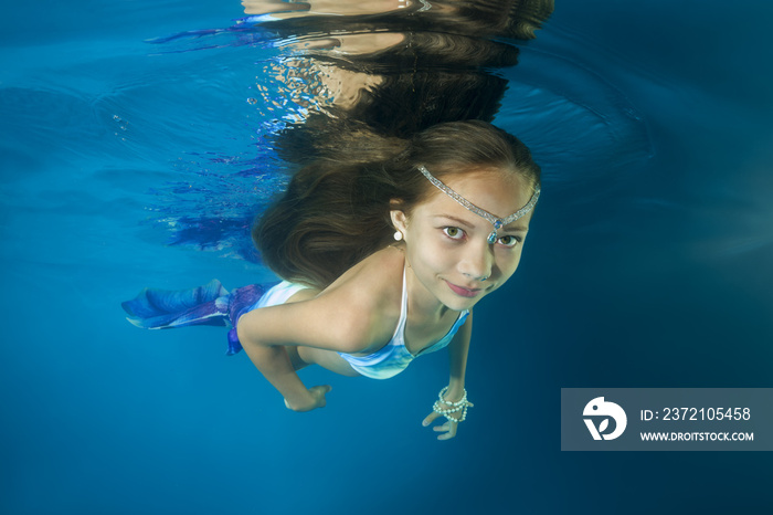 A girl in a mermaid costume poses underwater in a pool. Underwater girls pictures