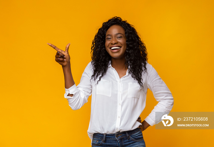 Laughing afro woman in white shirt pointing away