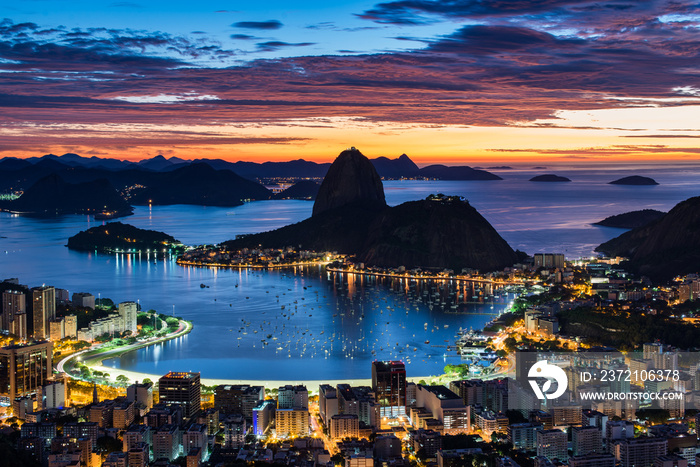 Rio de Janeiro city just before sunrise with city lights on, and the Sugarloaf Mountain in the horiz