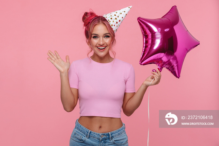 Portrait of beautiful woman wearing party cone holding air balloon