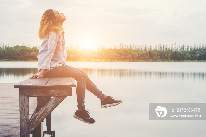 Young beautiful hipster woman sitting on the lake relaxing with